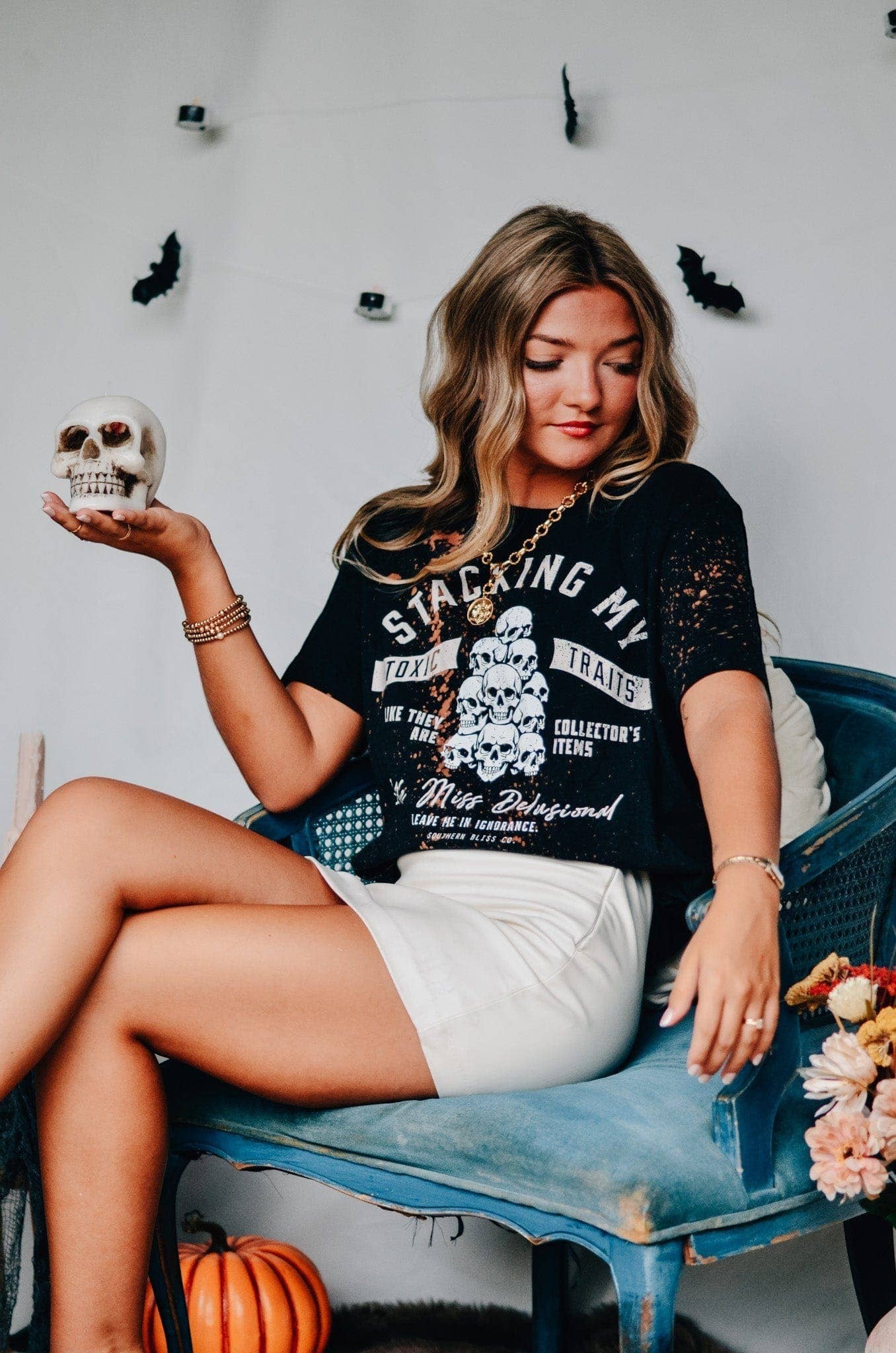 Doodlations Coffee Bar & Boutique black bleached graphic tee with skull print worn by a woman holding a skull prop