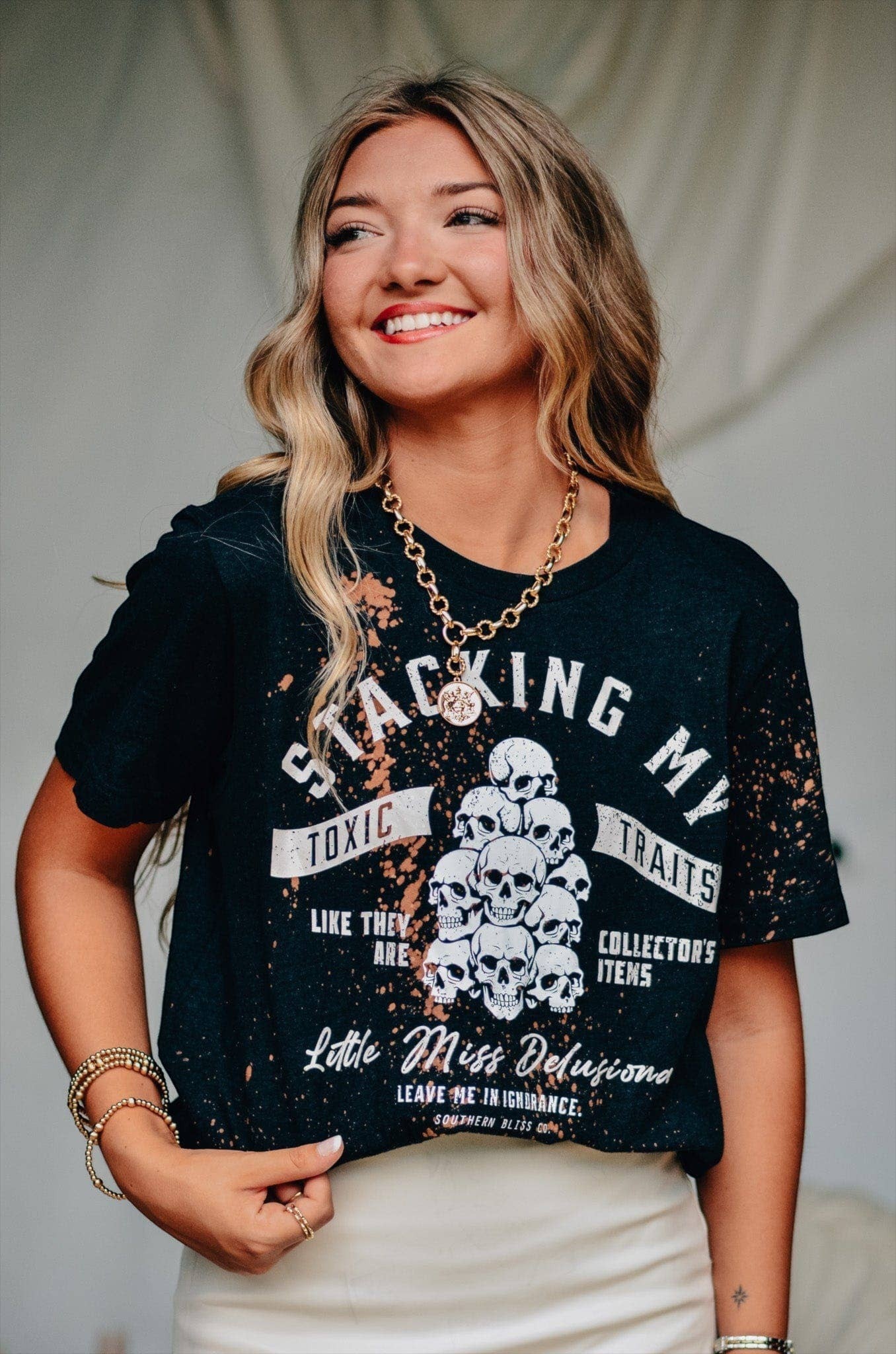 Doodlations Coffee Bar & Boutique black bleached graphic t-shirt with skull print worn by a smiling woman