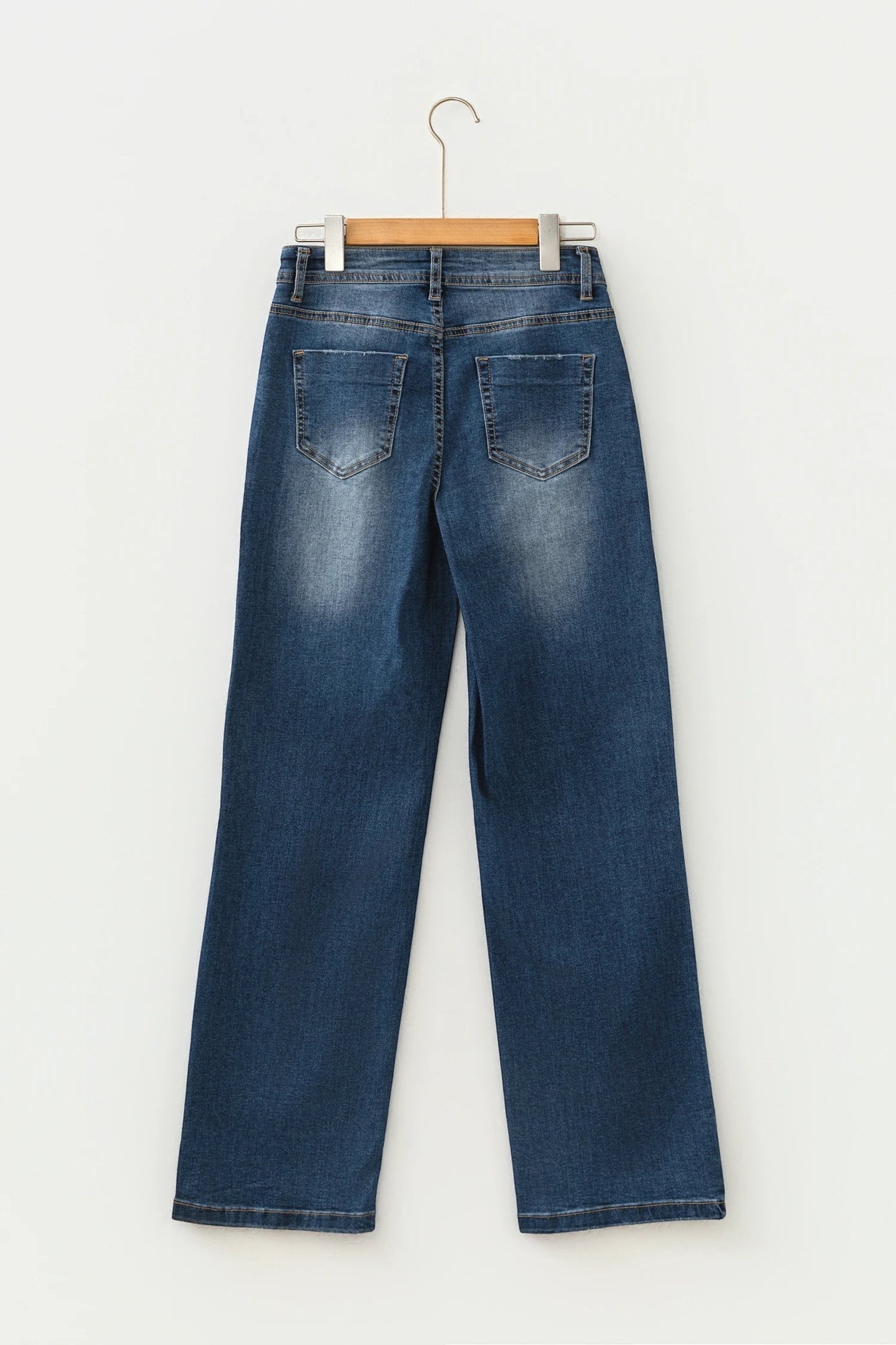 Doodlations Coffee Bar & Boutique blue acid washed straight leg denim jeans, back view on a wooden hanger.
