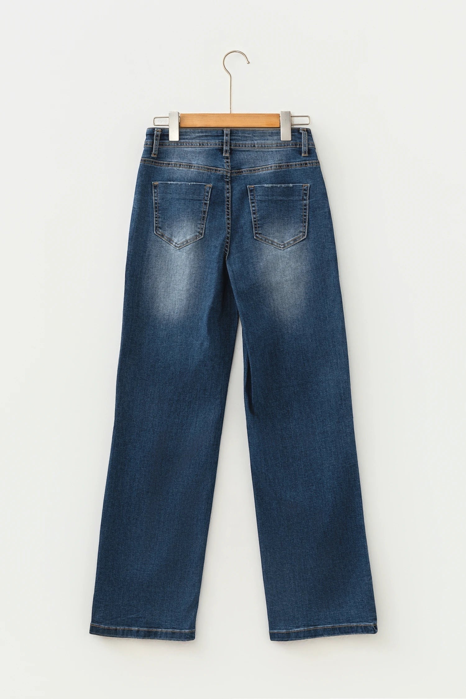 Doodlations Coffee Bar & Boutique blue acid washed straight leg denim jeans, back view on a wooden hanger.