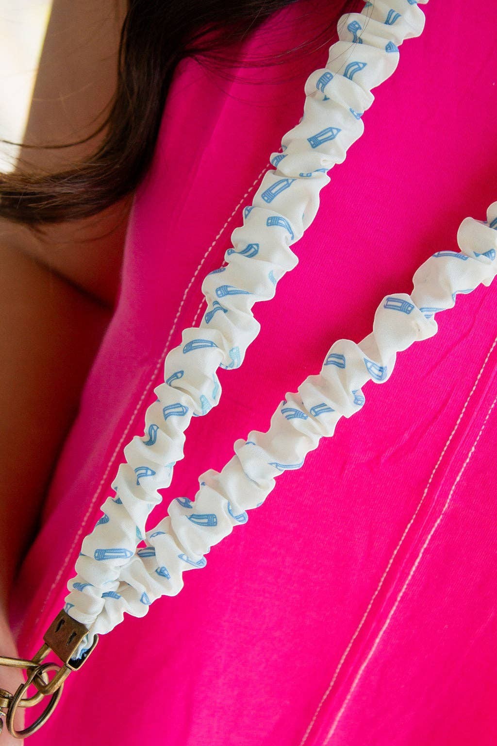 Doodlations Coffee Bar & Boutique blue pencil print polyester lanyard worn over a bright pink shirt