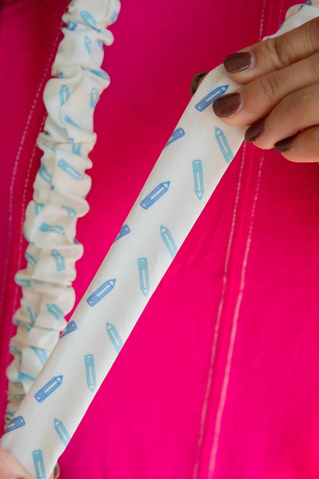 Doodlations Coffee Bar & Boutique blue pencil print polyester lanyard held against a bright pink background
