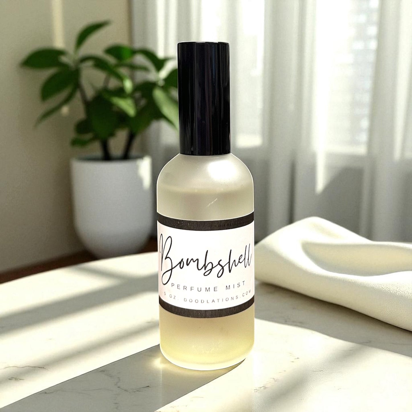 Doodlations Coffee Bar & Boutique Bombshell luxury fine mist perfume in a frosted glass bottle on a white surface.