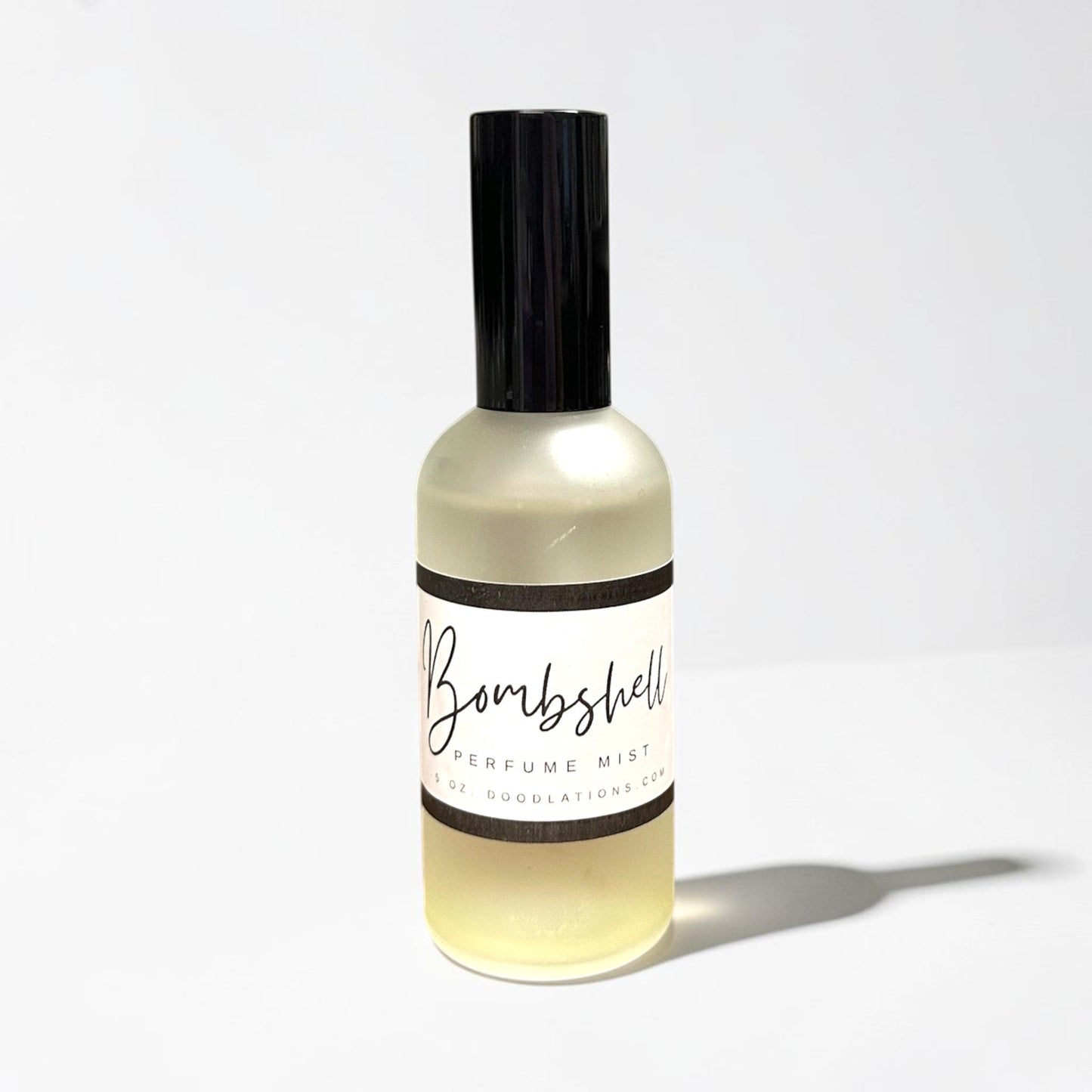 Doodlations Coffee Bar & Boutique Bombshell luxury fine mist perfume in a clear glass bottle with a black cap.