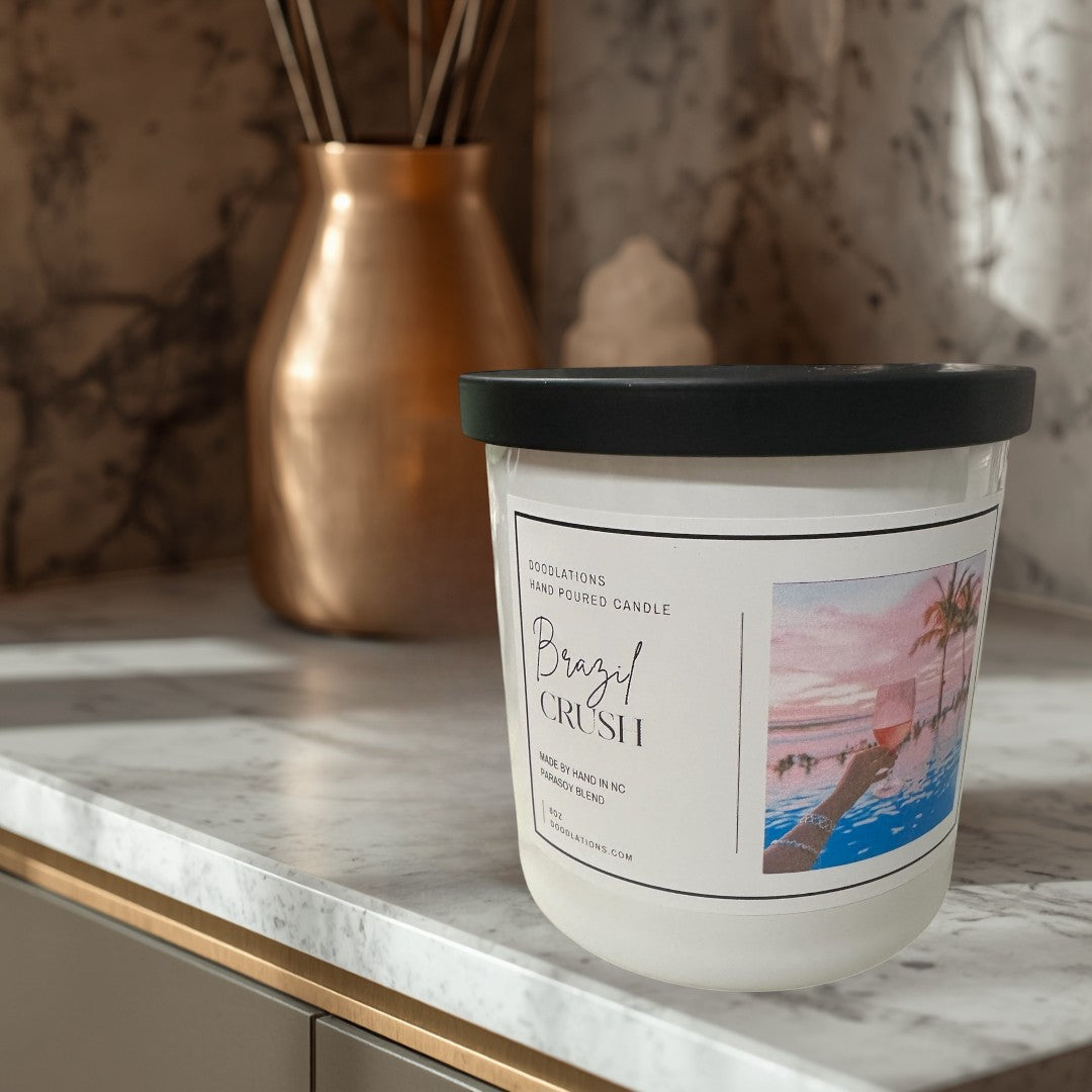 Doodlations Coffee Bar & Boutique Brazilian Crush hand-poured soy blend candle with a tropical sunset label.