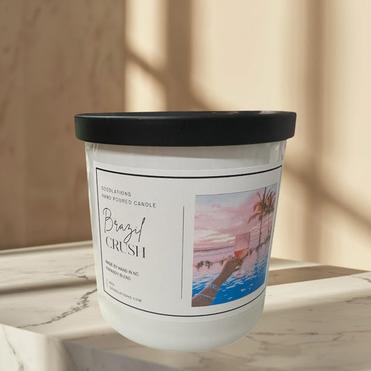 Doodlations Coffee Bar & Boutique Brazilian Crush hand-poured soy blend candle with tropical sunset label.