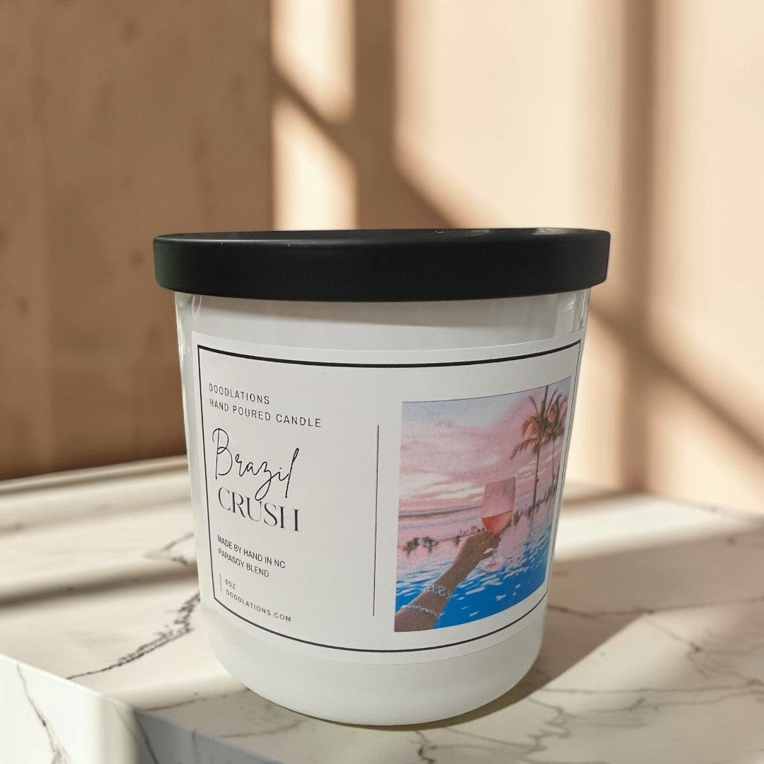 Doodlations Coffee Bar & Boutique Brazilian Crush hand-poured soy blend candle with tropical sunset label.
