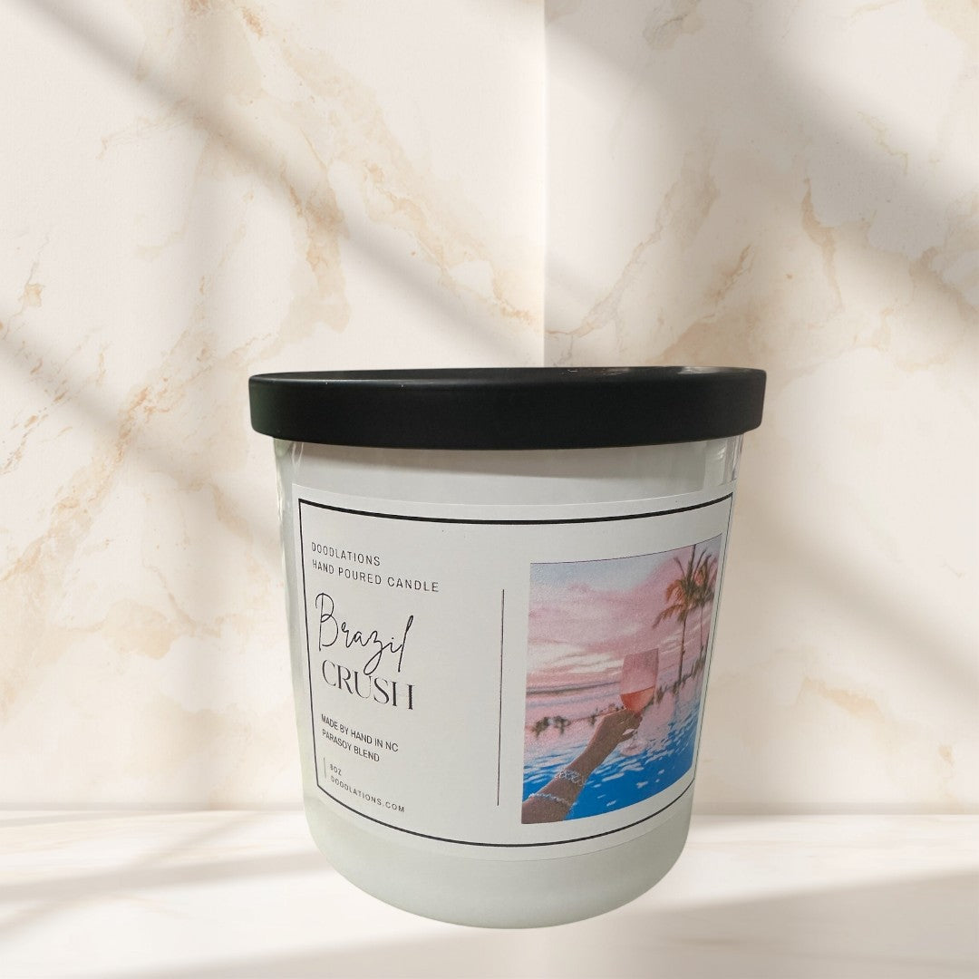 Doodlations Coffee Bar & Boutique Brazilian Crush hand-poured soy blend candle with tropical sunset label.