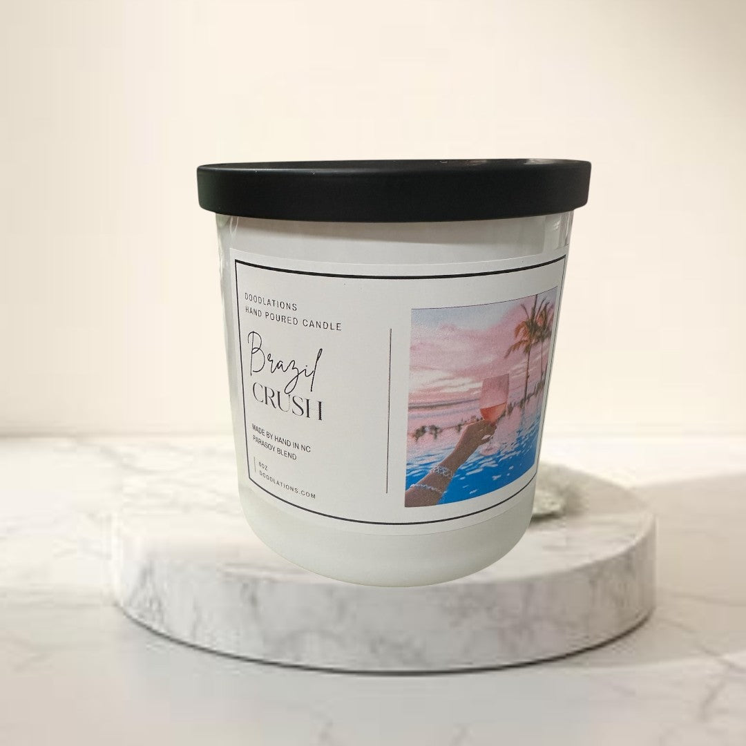 Doodlations Coffee Bar & Boutique Brazilian Crush hand-poured soy blend candle with tropical sunset label.