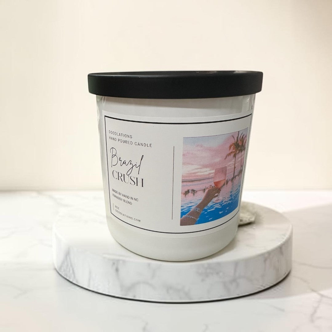 Doodlations Coffee Bar & Boutique Brazilian Crush hand-poured soy blend candle with tropical sunset label.