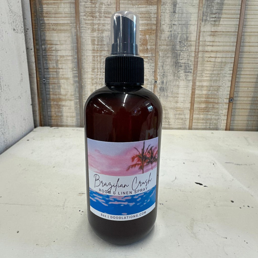 Doodlations Coffee Bar & Boutique Brazilian Crush room and linen spray in amber bottle with tropical sunset label.