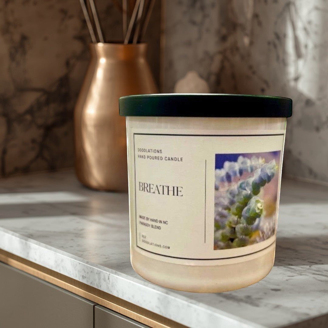 Doodlations Coffee Bar & Boutique Breathe luxury hand-poured soy wax candle with a calming scent, in a white jar with a black lid.