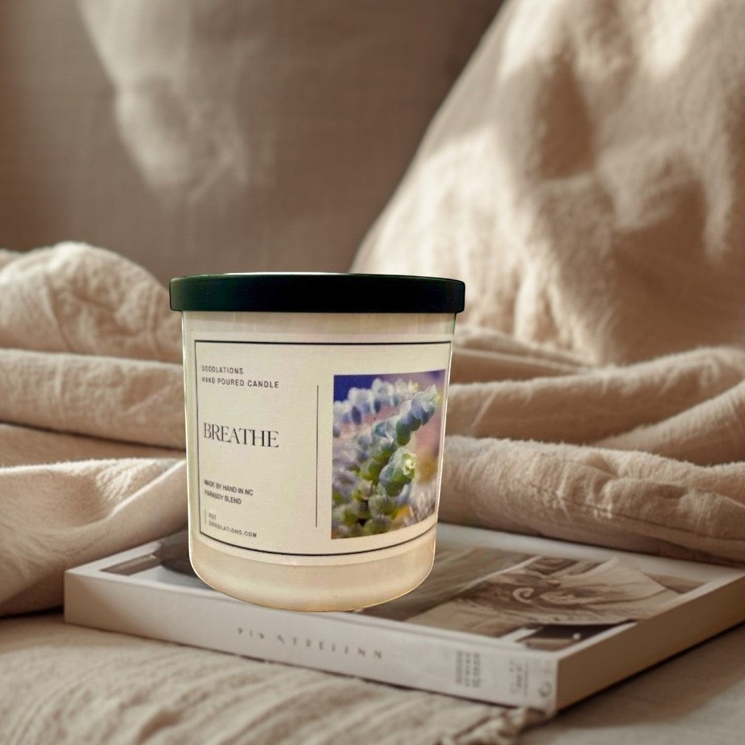 Doodlations Coffee Bar & Boutique Breathe hand-poured soy blend candle with a calming scent profile. White jar with black lid.