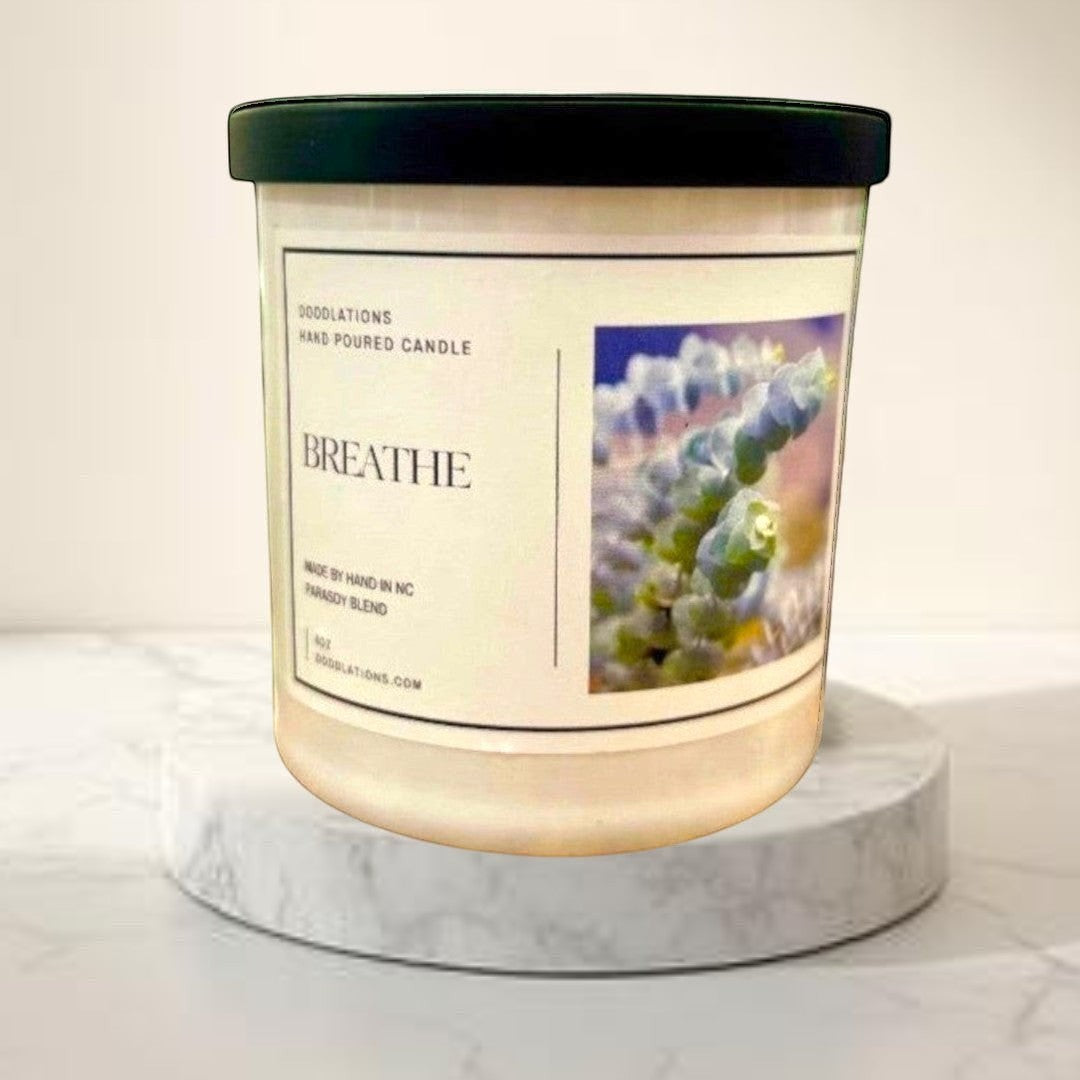 Doodlations Coffee Bar & Boutique Breathe luxury hand-poured candle in a white jar with a black lid, featuring a calming scent profile.