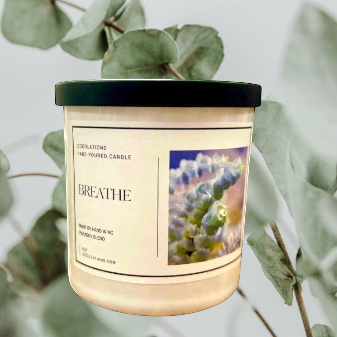 Doodlations Coffee Bar & Boutique Breathe luxury hand-poured candle in a white jar with a black lid, featuring a calming scent profile.