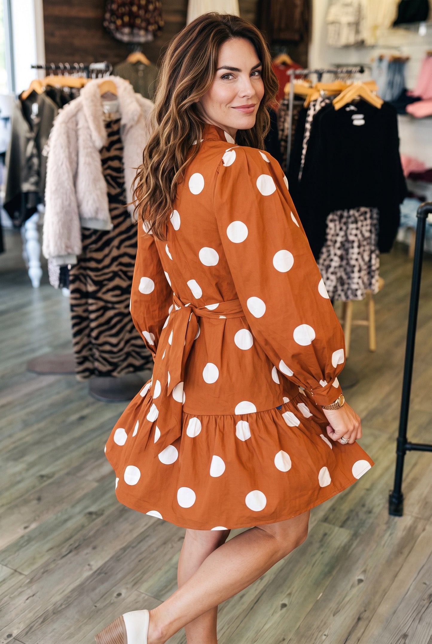 Doodlations Coffee Bar & Boutique brown mini dress with white polka dots, long sleeves, and a tie waist detail.