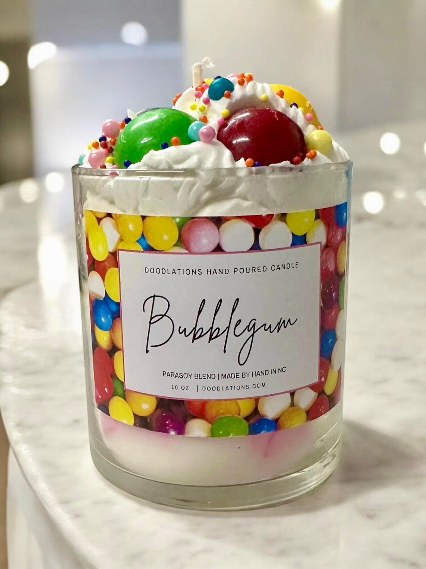 Doodlations Coffee Bar & Boutique Bubblegum candle with a playful design, topped with whipped wax, candy, and sprinkles.