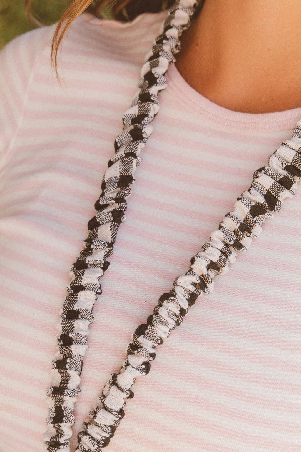 Doodlations Coffee Bar & Boutique black and white buffalo check fabric lanyard worn around the neck