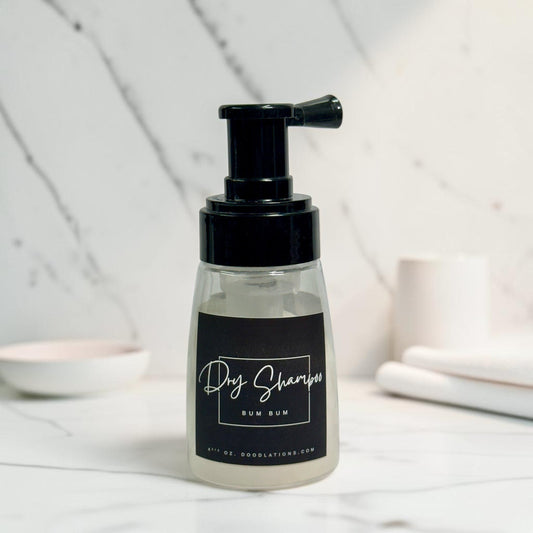 Doodlations Coffee Bar & Boutique Bum Bum dry powder shampoo in a clear pump bottle with a black label on marble