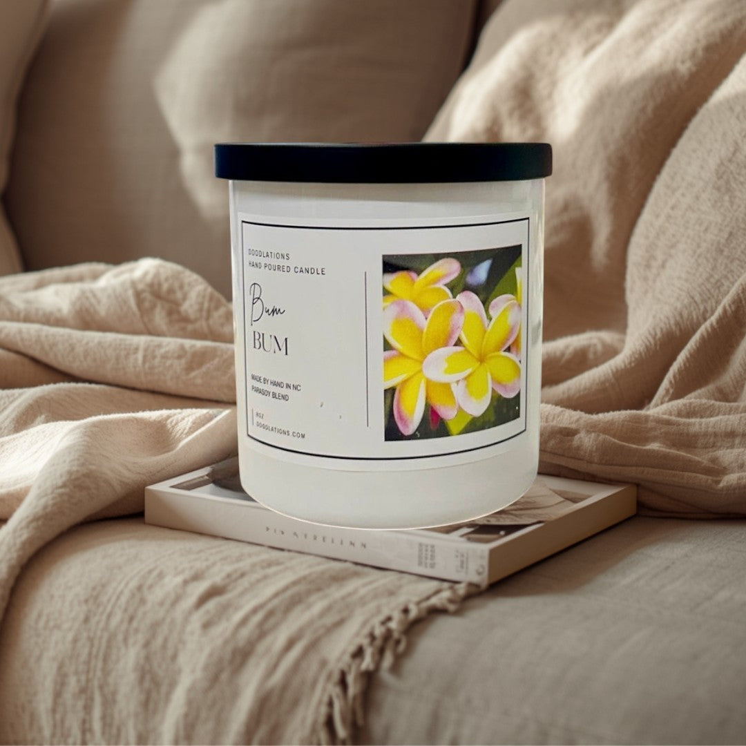 Doodlations Coffee Bar & Boutique Bum Bum luxury candle in a white jar with a black lid, featuring a tropical floral label.