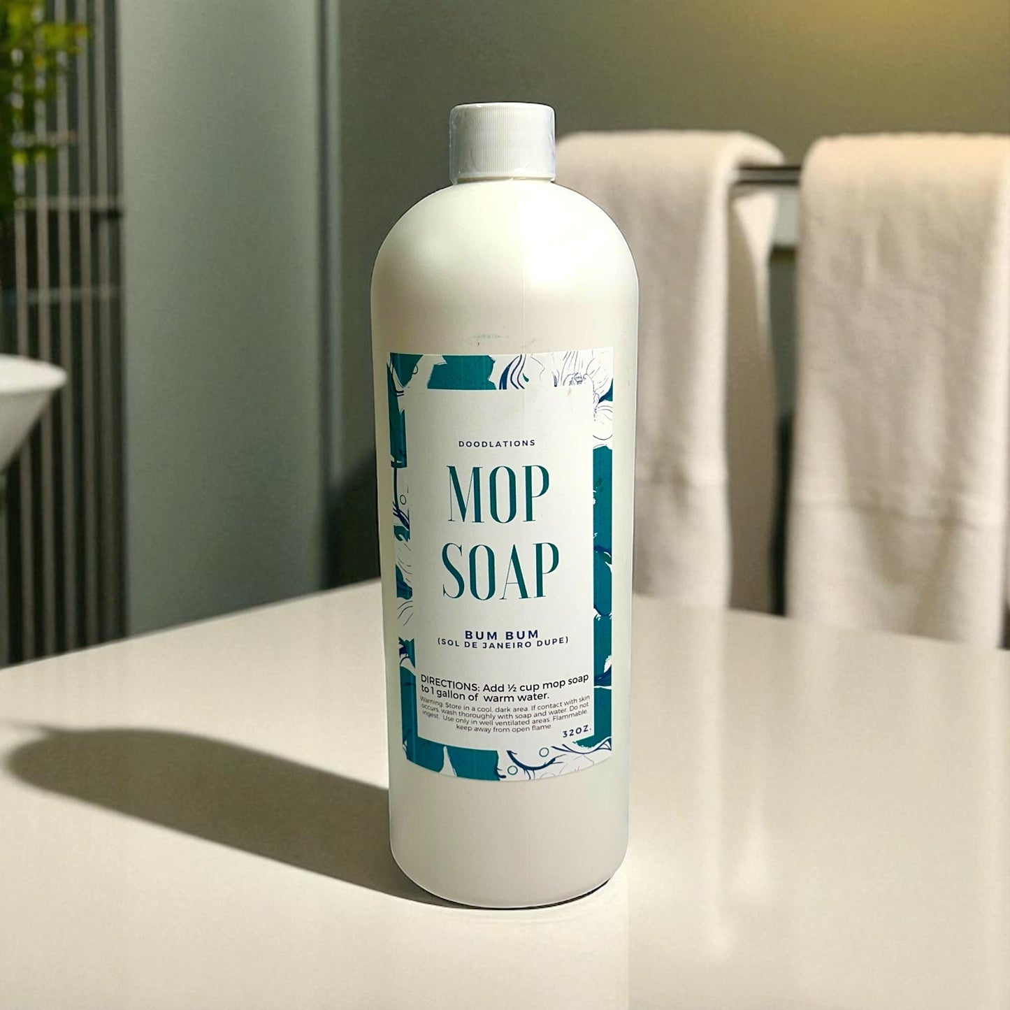 Doodlations Coffee Bar & Boutique Bum Bum concentrated mop soap, 32 oz bottle with tropical floral label. Beach-inspired scent.