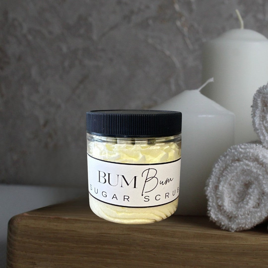 Doodlations Coffee Bar & Boutique Bum Bum Sugar Scrub in a clear jar with a black lid. Light yellow scrub with a textured surface.