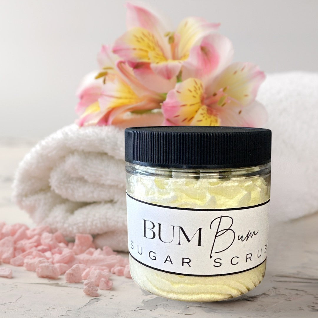 Doodlations Coffee Bar & Boutique Bum Bum Sugar Scrub in a clear jar with a black lid. Yellow scrub with a creamy texture.