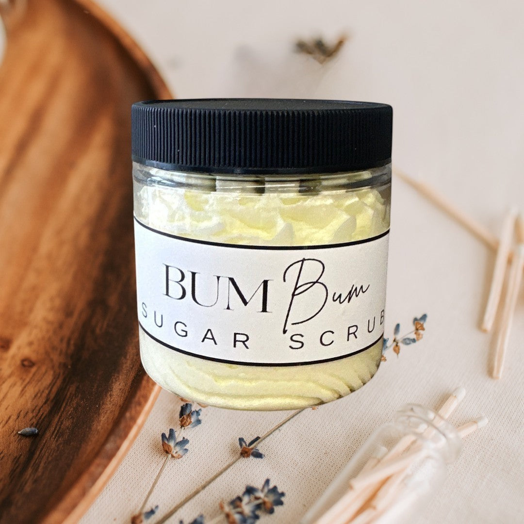 Doodlations Coffee Bar & Boutique Bum Bum Sugar Scrub in a clear jar with a black lid. Yellow scrub with a creamy texture.