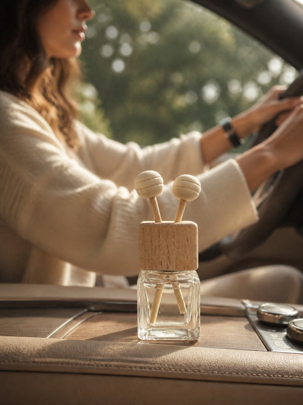 Doodlations Coffee Bar & Boutique car air freshener with a glass bottle and wooden vent clip inside a vehicle.