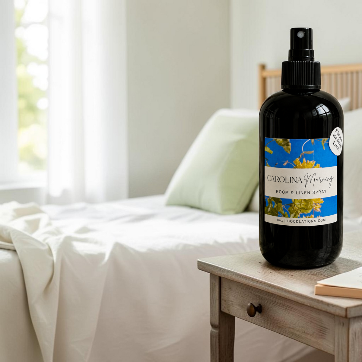 Doodlations Coffee Bar & Boutique Carolina Morning room and linen spray in a black bottle on a bedside table.
