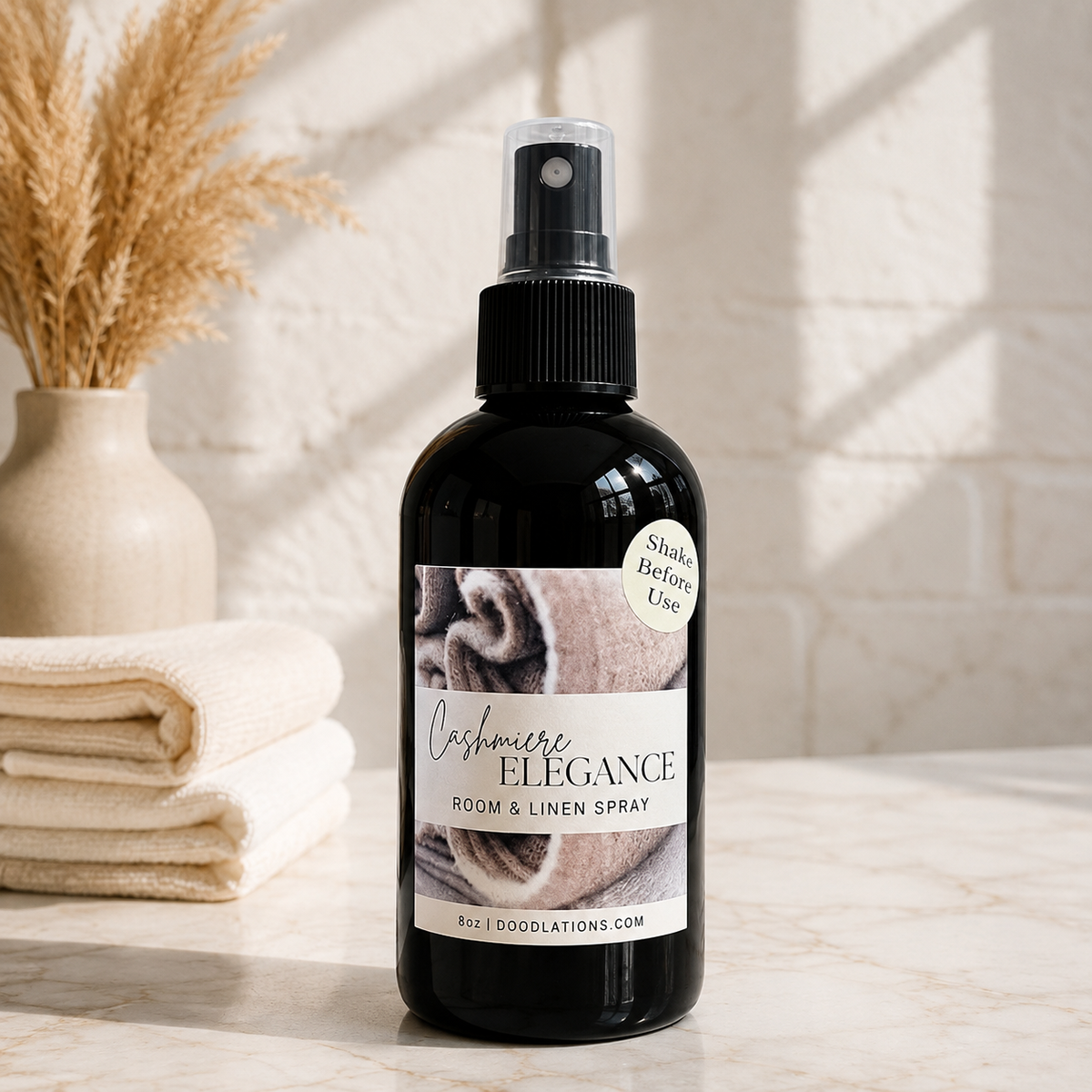 Doodlations Coffee Bar & Boutique Cashmere Elegance room and linen spray in a black bottle on a marble surface.