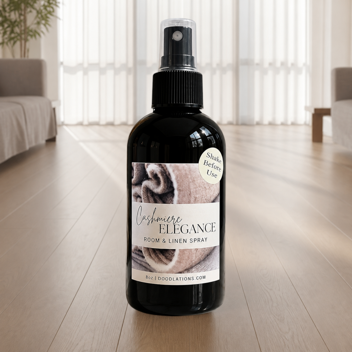 Doodlations Coffee Bar & Boutique Cashmere Elegance room and linen spray in a black 8oz bottle on a wooden floor.