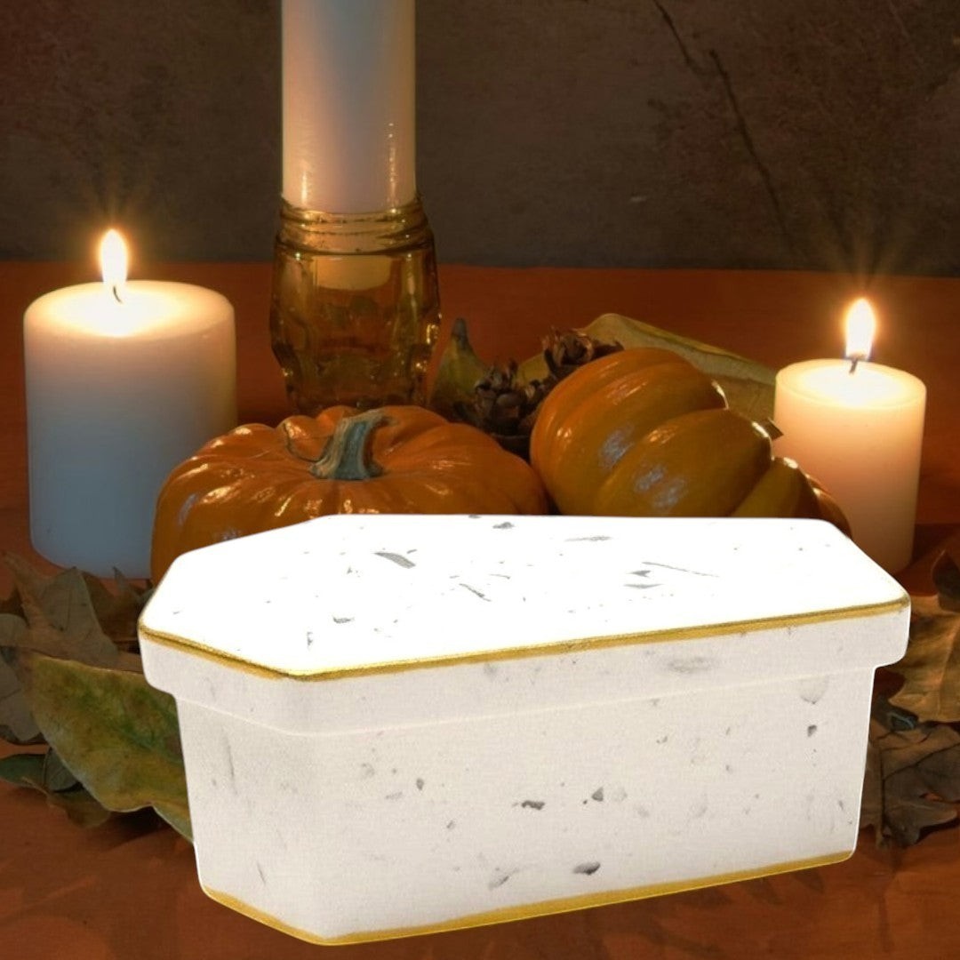 Doodlations Coffee Bar & Boutique white concrete casket candle with gold trim and speckled details.
