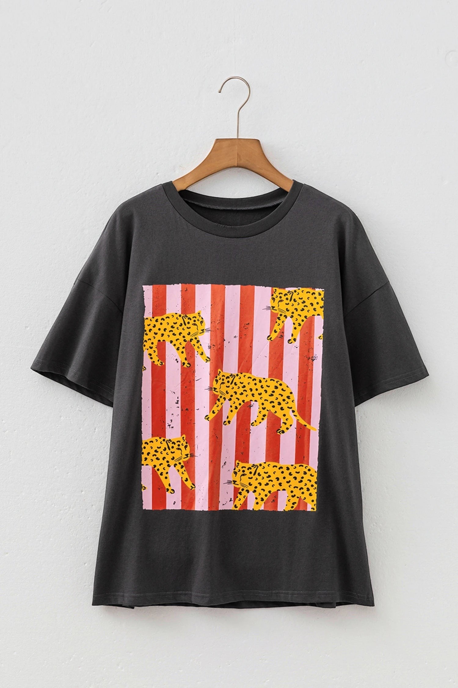 Doodlations Coffee Bar & Boutique dark grey graphic tee with a retro cheetah and red striped print on a hanger.