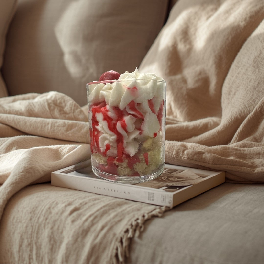 Doodlations Coffee Bar & Boutique Cherry Cheesecake candle in a glass jar, resembling dessert with white cream and red drizzle.