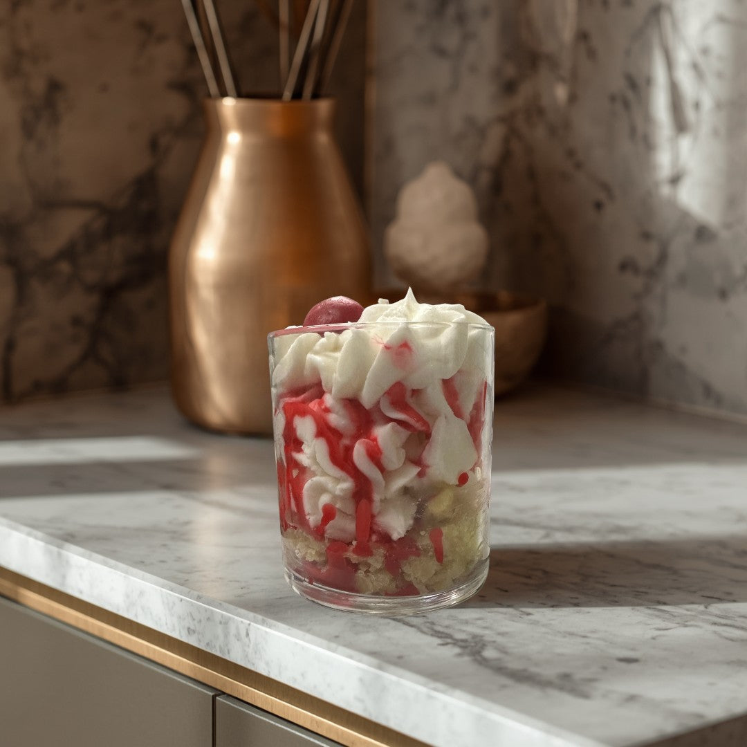 Doodlations Coffee Bar & Boutique Cherry Cheesecake candle in a glass jar, resembling dessert with white cream and red drizzle.