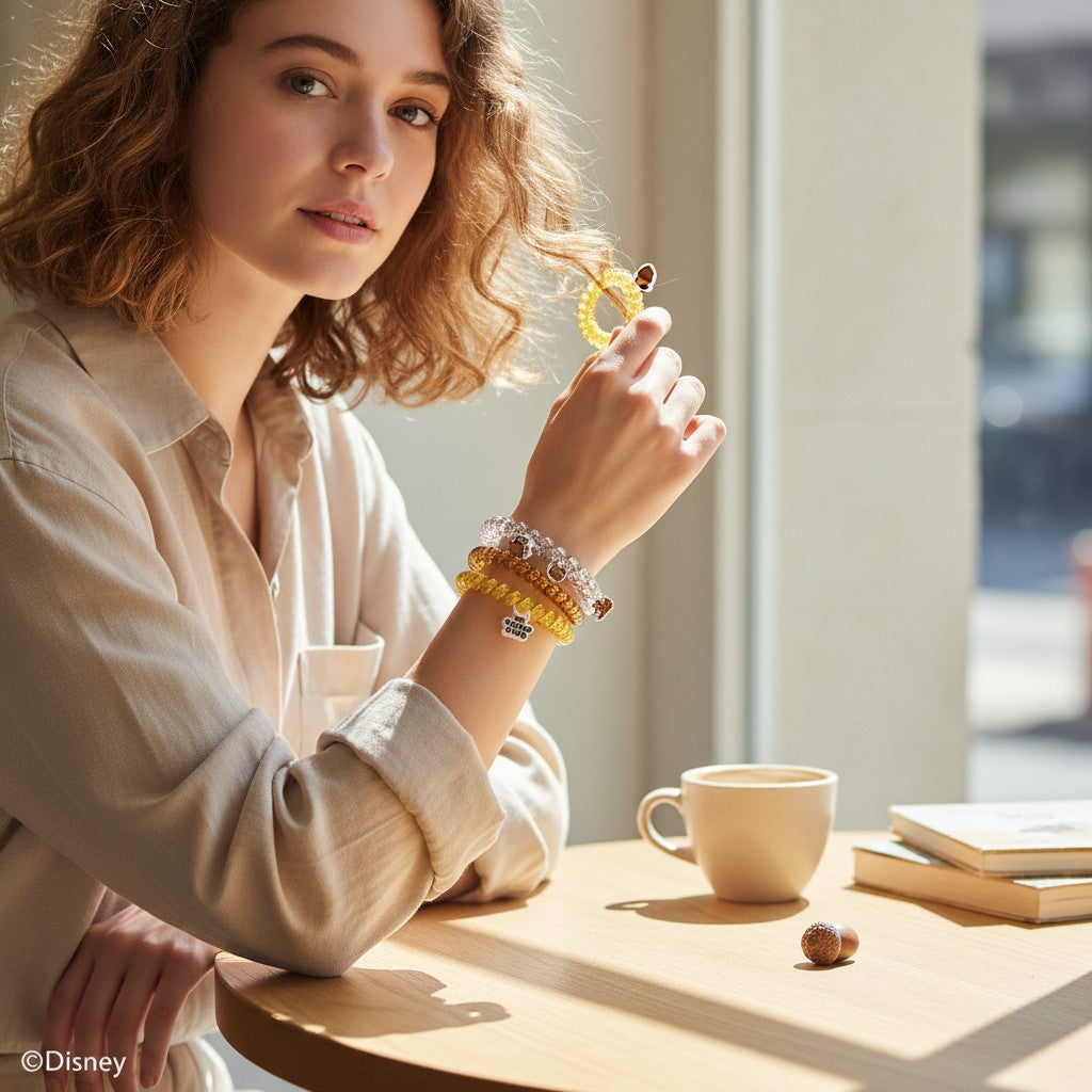 A woman wearing Doodlations Coffee Bar & Boutique Disney Chip 'N Dale hair ties as bracelets while sitting at a table