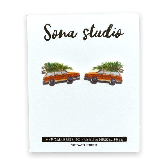 Doodlations Coffee Bar & Boutique Christmas wagon earrings featuring orange station wagons with pine trees on top.