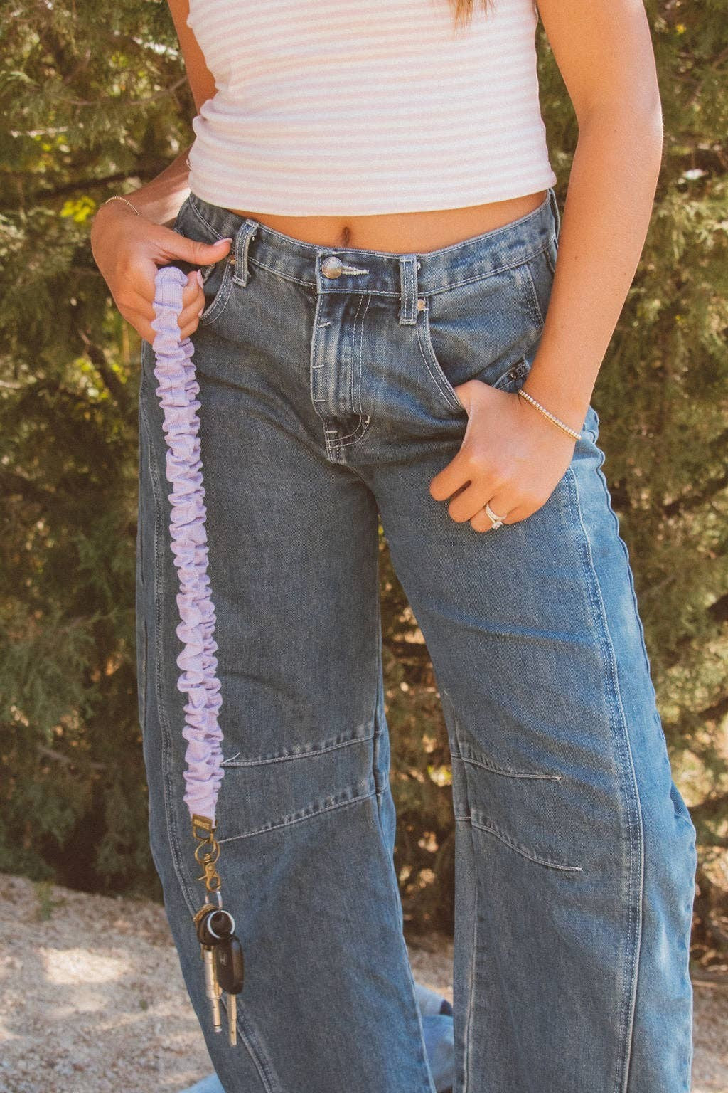 Doodlations Coffee Bar & Boutique chunky purple textured fabric lanyard held by a person wearing jeans and a white top
