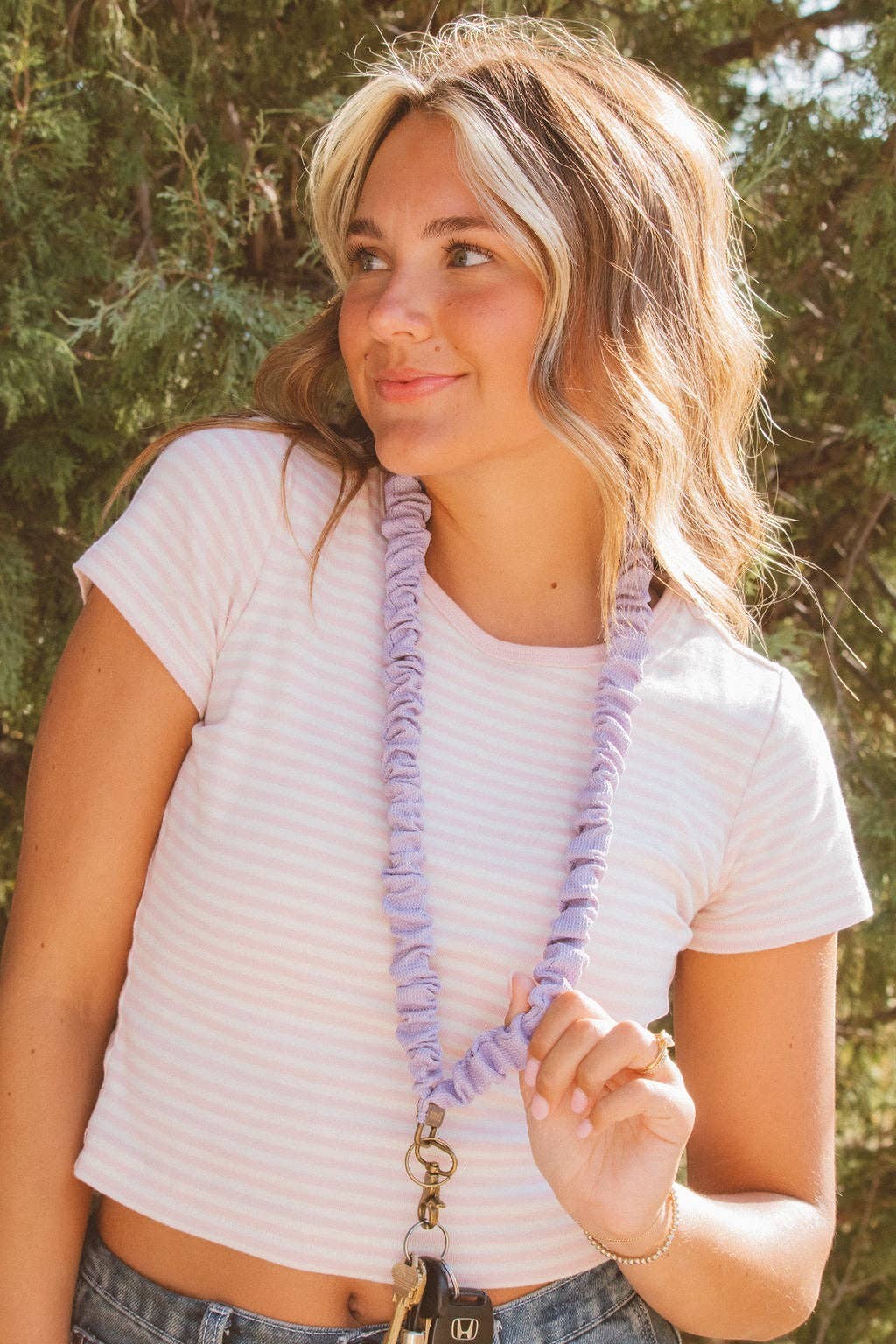 Doodlations Coffee Bar & Boutique chunky purple textured lanyard worn by a woman in a striped t-shirt outdoors