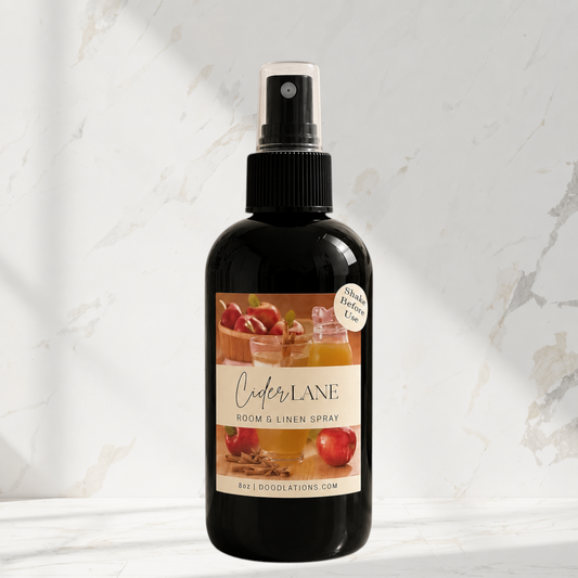 Doodlations Coffee Bar & Boutique Cider Lane room and linen spray in a black bottle with an apple and spice label.