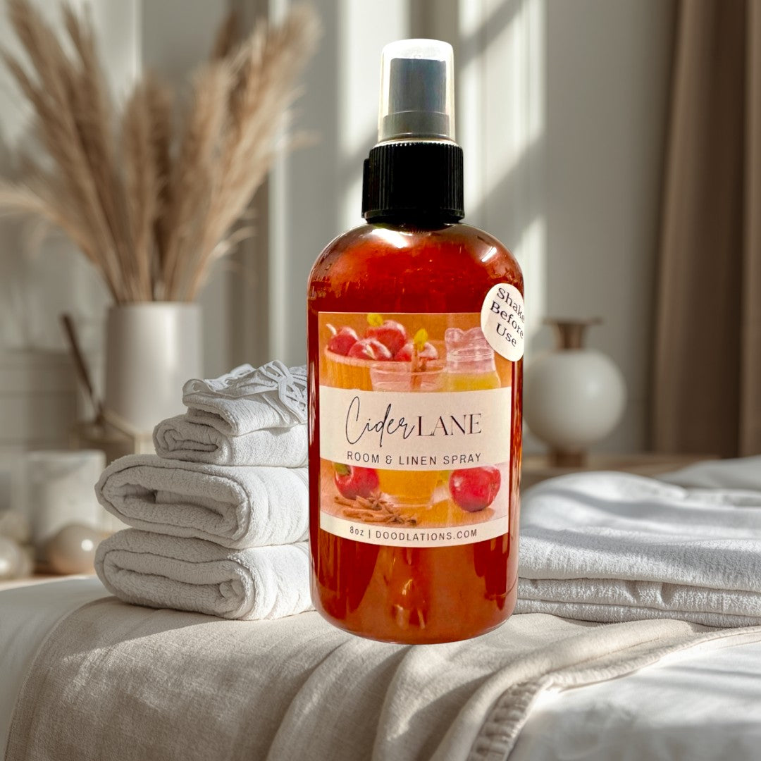 Doodlations Coffee Bar & Boutique Cider Lane Room & Linen Spray in amber bottle with apple and cinnamon label.