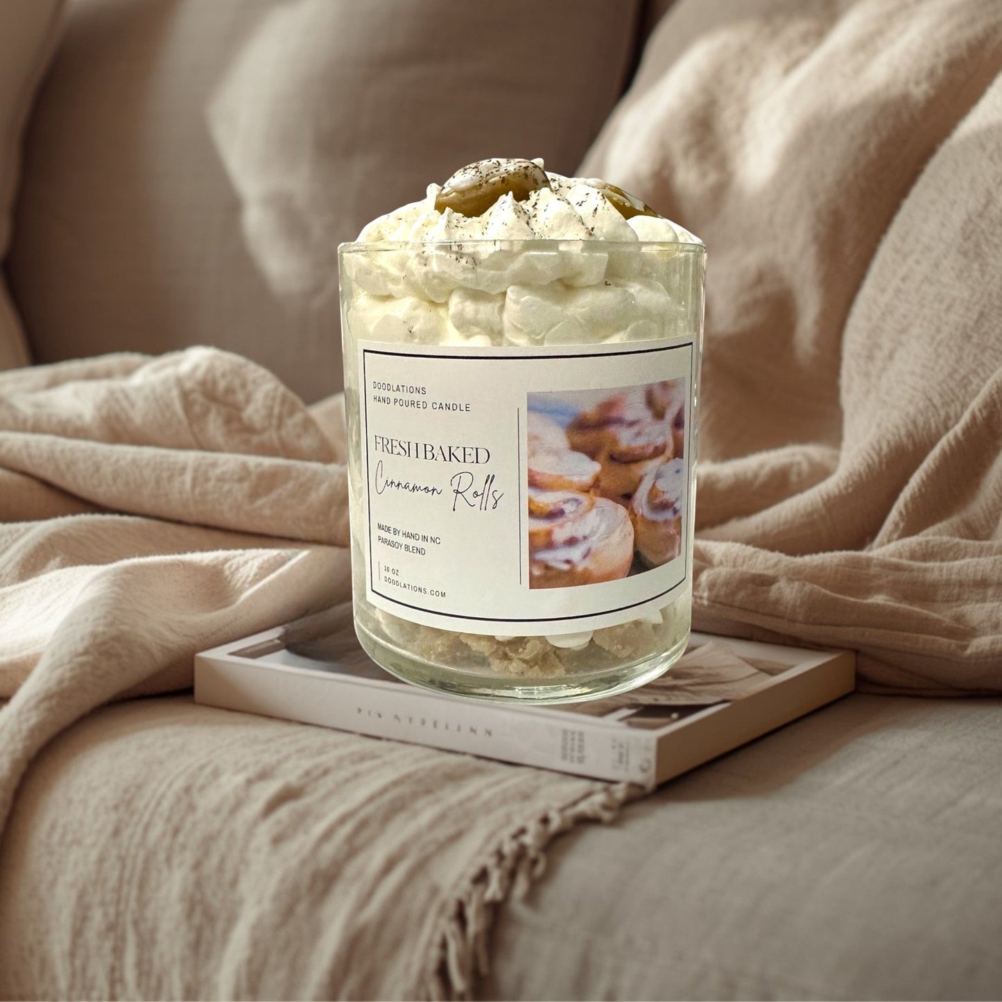 Doodlations Coffee Bar & Boutique Cinnamon Bun candle with decorative wax toppings resembling cinnamon rolls and whipped cream.