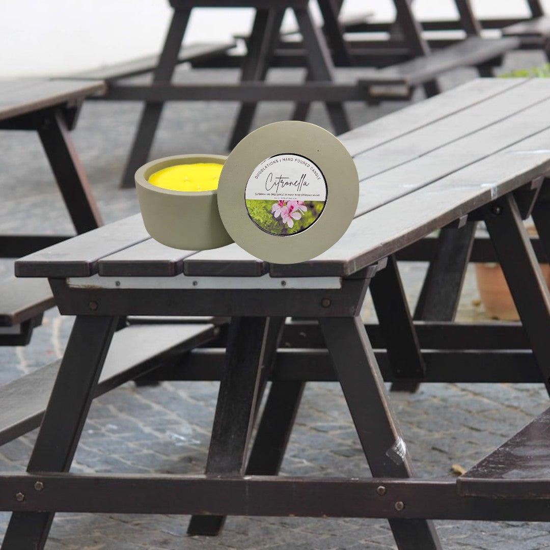 Doodlations Coffee Bar & Boutique 3-wick citronella candle in a grey concrete vessel with yellow wax. Outdoor use.