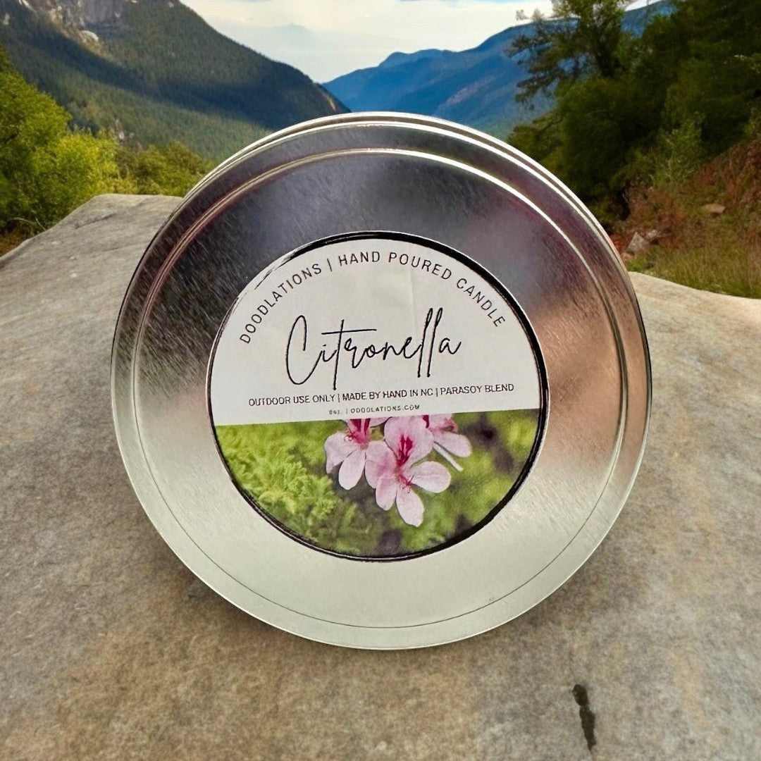 Doodlations Coffee Bar & Boutique Citronella outdoor candle in a silver tin with a label featuring pink flowers and greenery.
