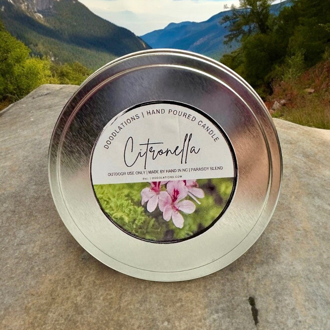 Doodlations Coffee Bar & Boutique Citronella outdoor candle in a silver tin with a label featuring pink flowers and greenery.