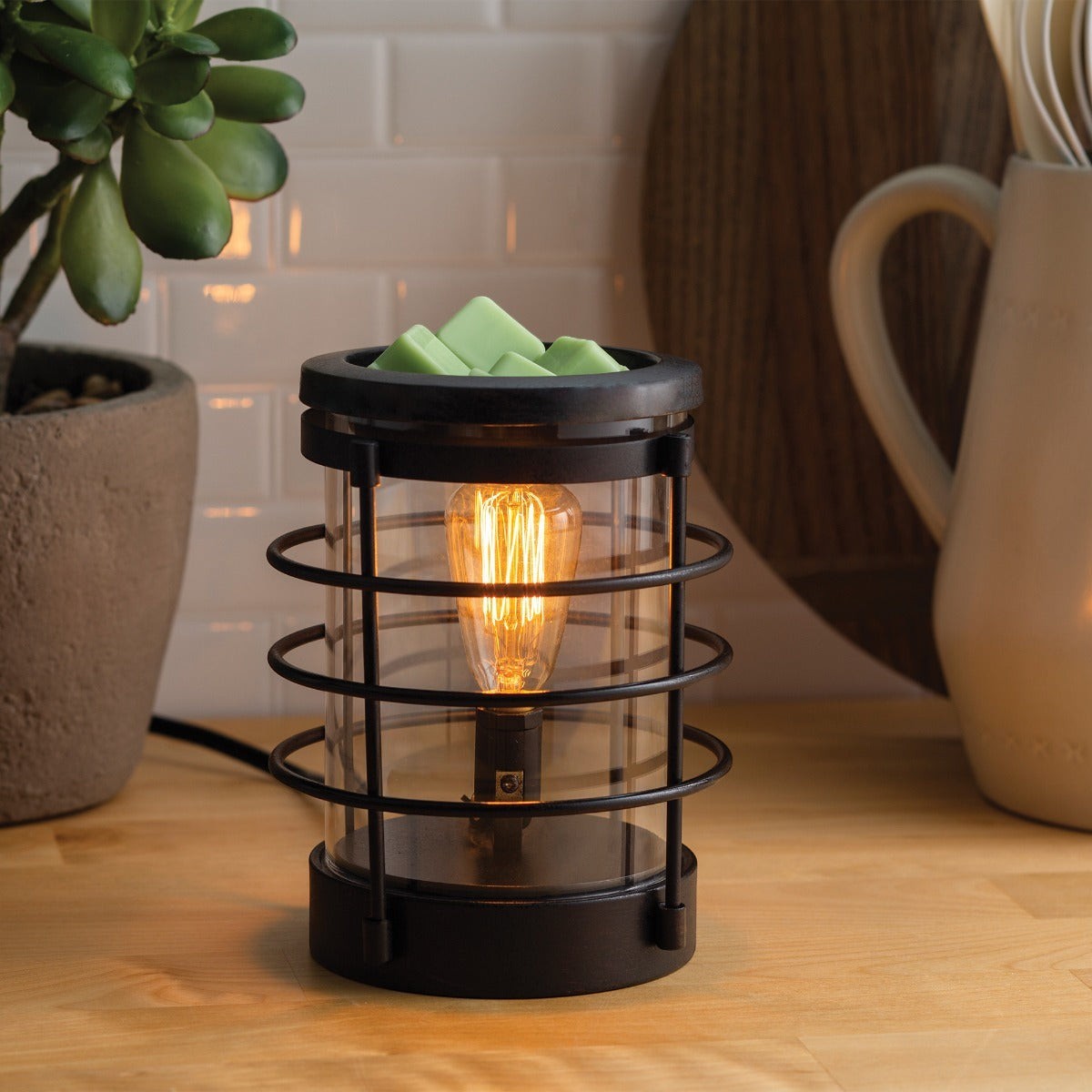 Doodlations Coffee Bar & Boutique Coastal Vintage Bulb Illumination wax warmer with green wax melts and a warm glowing bulb.