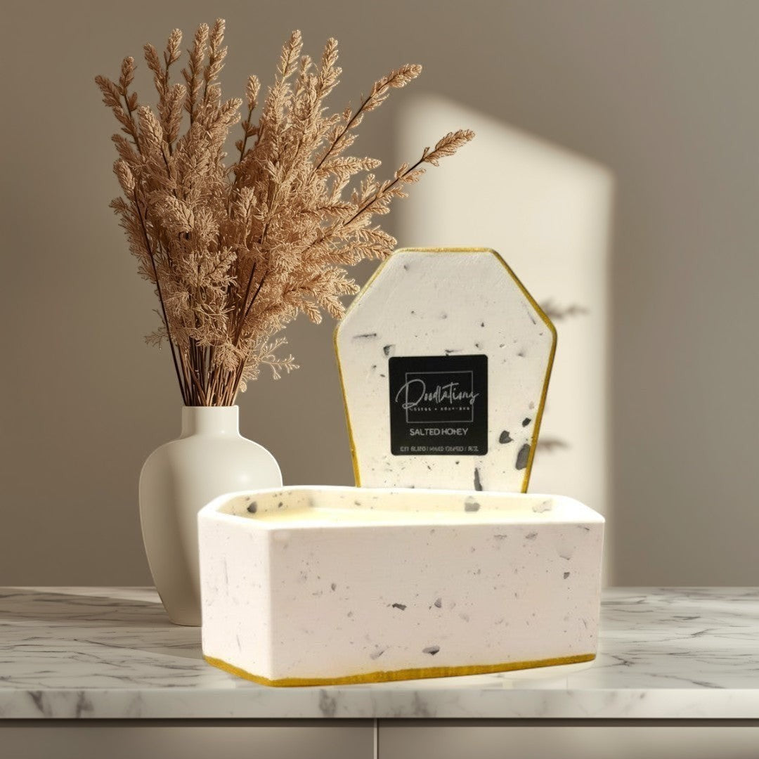 Doodlations Coffee Bar & Boutique casket-shaped concrete candle with two wicks, soy blend wax, and a gold rim.