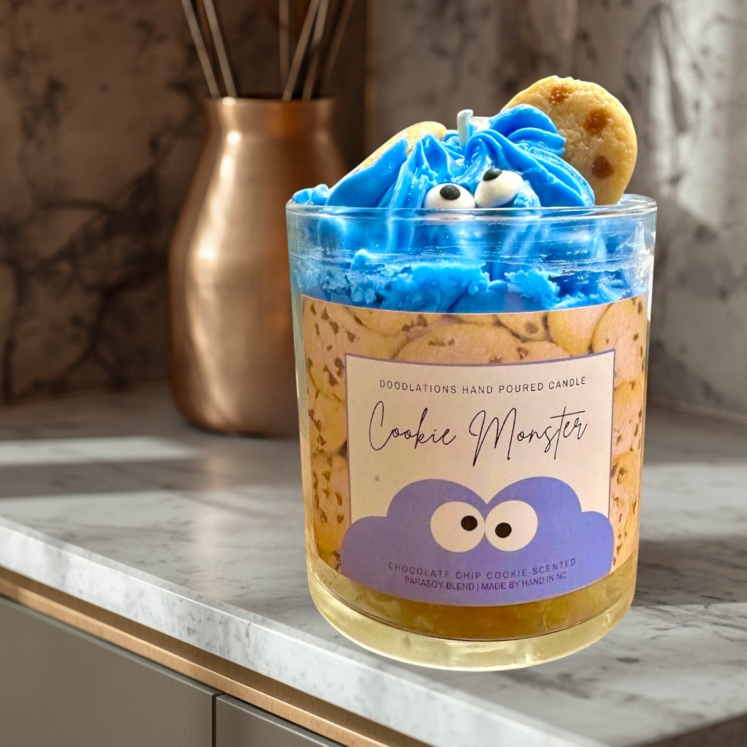 Doodlations Coffee Bar & Boutique Cookie Monster candle with blue frosting, googly eyes, and cookie accents. Chocolate chip cookie scent.