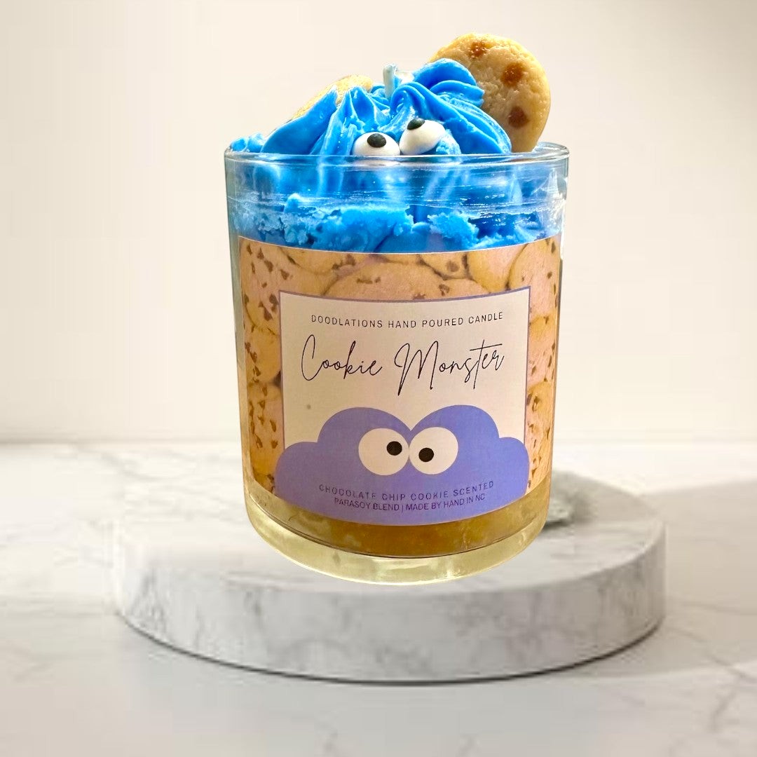 Doodlations Coffee Bar & Boutique Cookie Monster candle with blue frosting, googly eyes, and cookie accents. Chocolate chip cookie scent.
